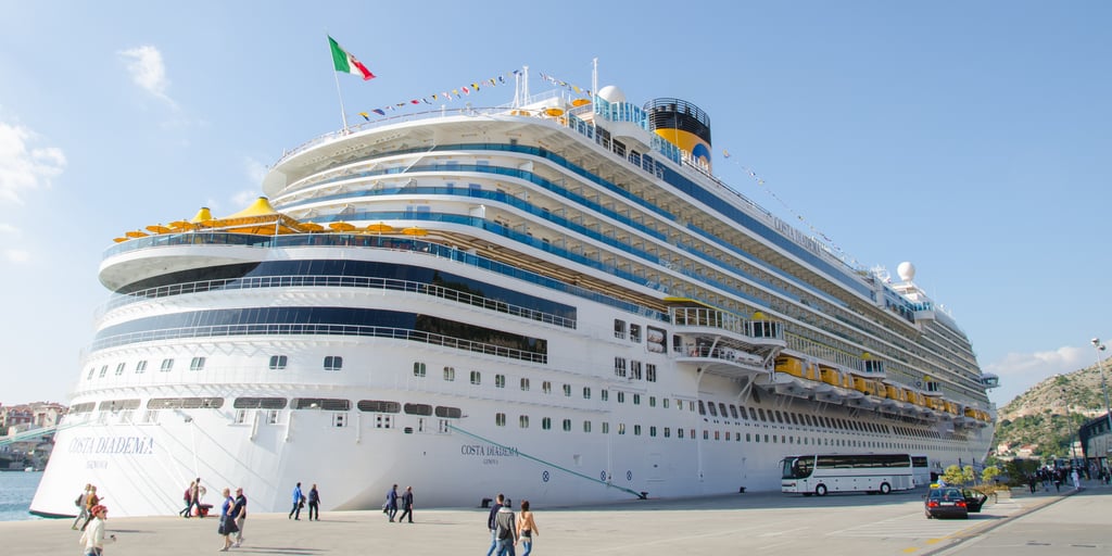 A large cruise ship moored at the quay of the port of Gruž in Dubrovnik, with passengers walking along the pier
