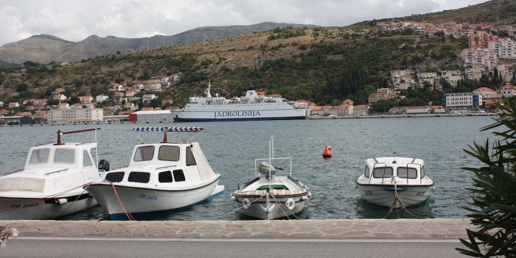 Small boats on the quay of Gruž harbour in Dubrovnik, with a Jadrolinija ferry at the port behind