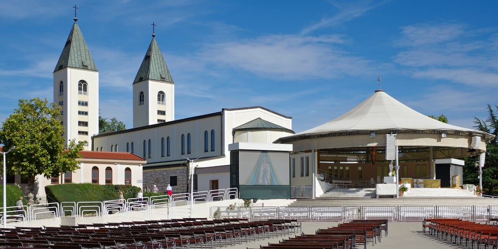 St James Church in Međugorje with its two bell towers, beside the outdoor altar and its rows of seats