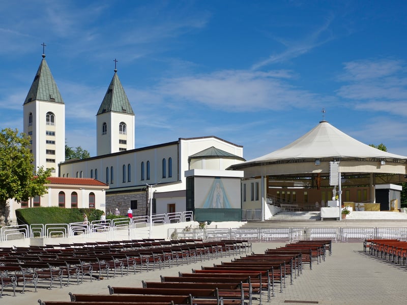 St James Church in Međugorje with its two bell towers, beside the outdoor altar and its rows of seats