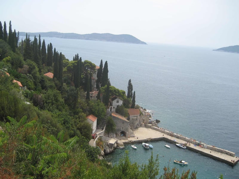 Trsteno's small harbour and stone houses among cypresses, seen from the arboretum above the sea